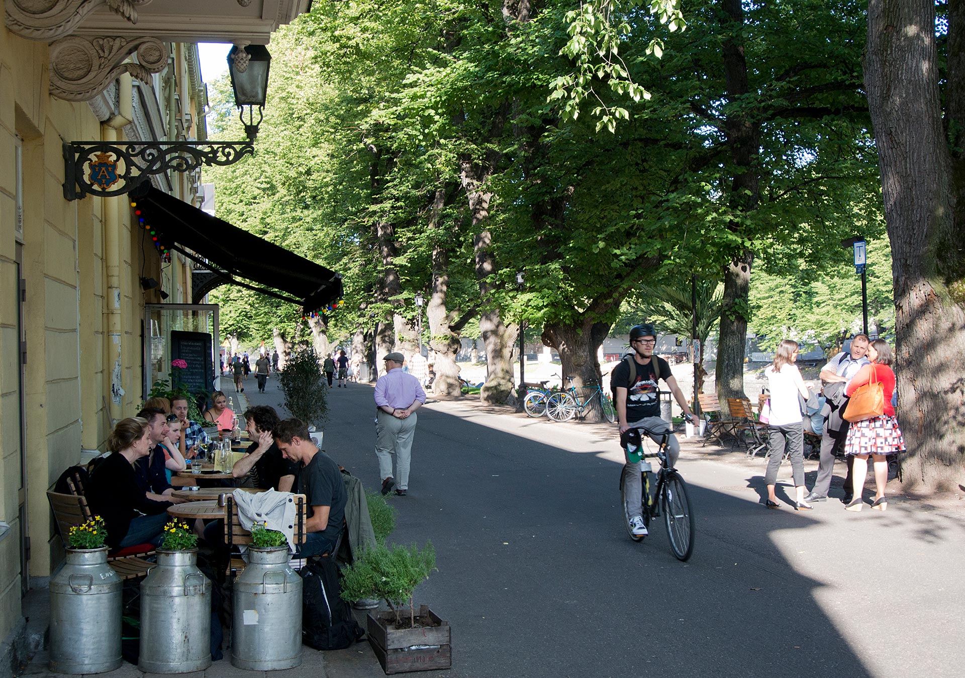 Pyöräilijä ajaa ravintolan terassin vierestä Turun Aurajoen rannassa,